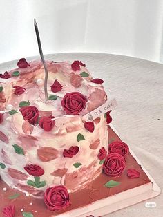 a cake that has been decorated with red roses on it and is sitting on a table