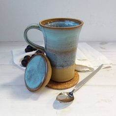 a coffee cup sitting on top of a wooden table next to a spoon and fork