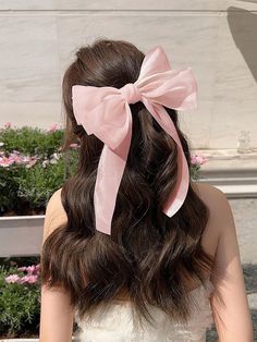 a woman wearing a white dress with a pink bow on her head and long hair