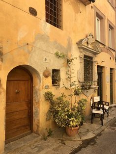 an old building with potted plants on the sidewalk