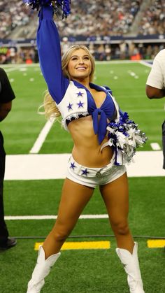 a cheerleader is posing on the field at a football game with her arms in the air