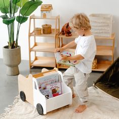 a little boy that is standing in front of a toy car and bookshelf