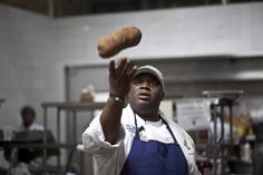 a woman in an apron tossing bread into the air