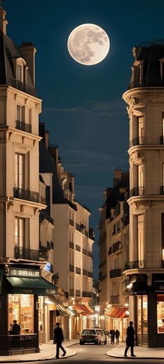 two people walking down the street in front of some buildings at night under a full moon