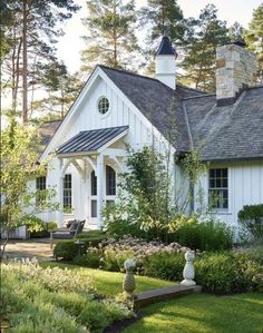 a white house surrounded by trees and flowers