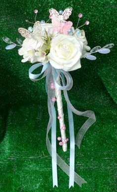 a bouquet with white roses and butterflies on top of green grass in front of a wall