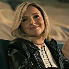 a woman sitting on top of a couch wearing a black leather jacket and white shirt