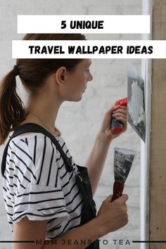 a woman holding a paint roller and painting the wall with text overlay that reads 5 unique travel wallpaper ideas