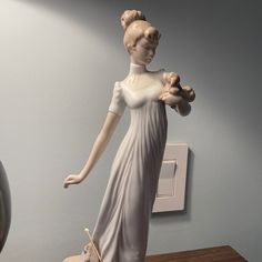 a statue of a woman in a white dress on a table next to a light switch