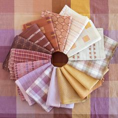 an assortment of different colored fabrics on a tablecloth with a circular hole in the middle