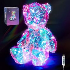 a lighted teddy bear sitting on top of a table next to a remote control and box