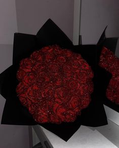 a black box with red roses in it on a counter top next to a mirror