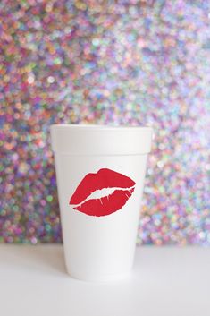 a cup with red lipstick painted on it sitting in front of a glittery background