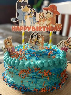 a birthday cake with blue frosting and sprinkles on the top is decorated with cartoon characters