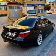 a black car parked in front of a yellow building