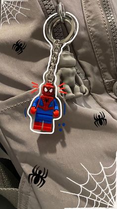 a spiderman keychain hanging from the side of a backpack