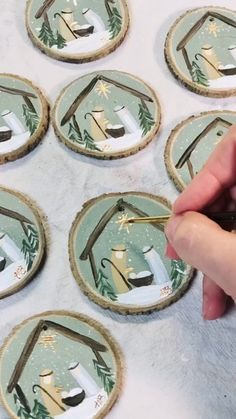 a person holding a pair of scissors in front of some coasters that have christmas decorations on them