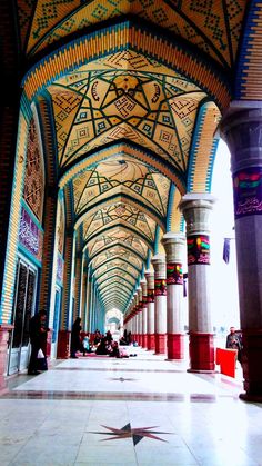 the inside of an ornate building with columns and arches on both sides, painted in bright colors