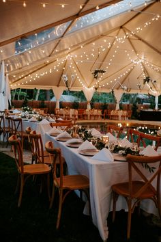 an outdoor tent with tables and chairs set up for dinner under string lights on the ceiling