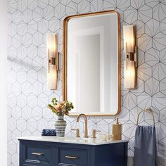 a bathroom with a blue vanity and gold accents on the wall, along with a large mirror