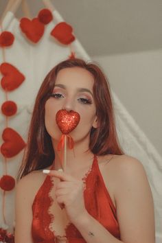 a woman in red dress holding up a heart shaped lollipop