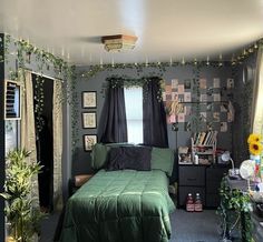 a bedroom decorated in green and black with flowers on the wall, plants hanging from the ceiling