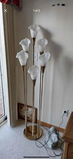 the floor lamp has four white flowers on it and is next to an open window