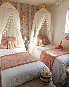 two white beds with pink comforters in a girls'bedroom, one has a teddy bear on the bed