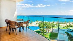 a balcony with chairs and table overlooking the ocean