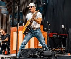 a man standing on top of a stage holding a guitar