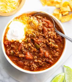 a bowl of chili with sour cream and tortilla chips