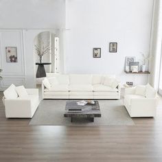 a living room with white furniture and wood floors