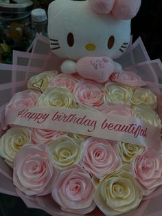 a hello kitty stuffed animal sitting on top of a bouquet of pink and white roses