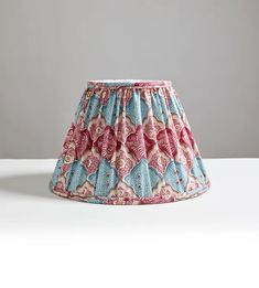 a pink and blue lamp shade sitting on top of a table