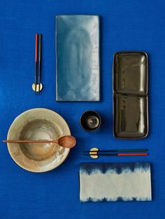 an assortment of items that include chopsticks, tea bag and spoon on a blue surface