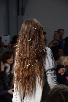 the back of a woman's head with long, curly hair in front of an audience