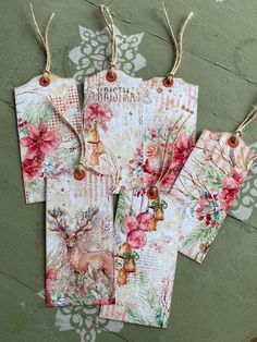 three tags with deer and flowers on them hanging from twine strings against a green wall