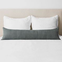 a bed with two pillows on top of it and one pillow is folded over the headboard