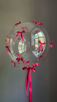 a large clear balloon with pink ribbons on it's side and a round window in the background