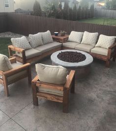 a fire pit sitting in the middle of a patio surrounded by wooden chairs and couches