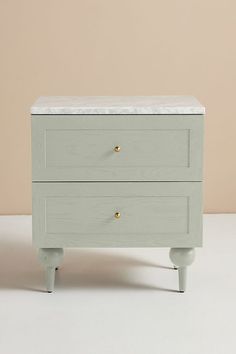 a white chest with two drawers on one side and gold knobs on the other