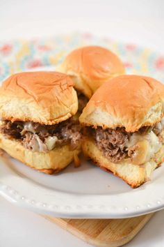 two hamburgers sitting on top of a white plate next to a wooden cutting board