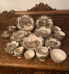 a table topped with lots of plates and bowls on top of a wooden table next to a wall