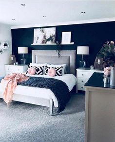 a bedroom decorated in black and white with pops of pink on the bed, nightstands