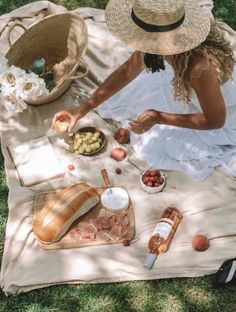 a woman sitting on top of a blanket next to food