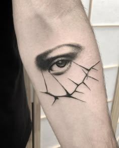 a man's arm with an eye and barbed wire tattoo on the left forearm