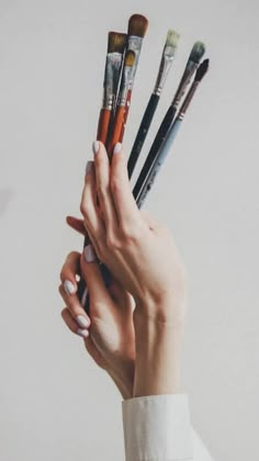 a person holding up six brushes in their hands with one hand on top of the other