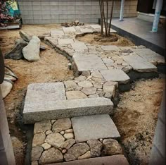 a stone bench sitting in the middle of a yard next to a tree and rocks