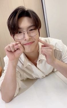 a young man wearing glasses sitting at a table