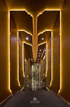 an elegant hallway is lit up with yellow lights and intricate designs on the walls, along with carpeted flooring